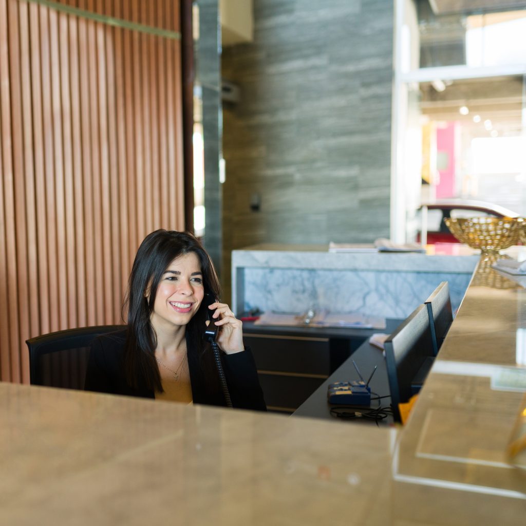 Receptionist answering phone at front desk — office support recruitment and staffing services