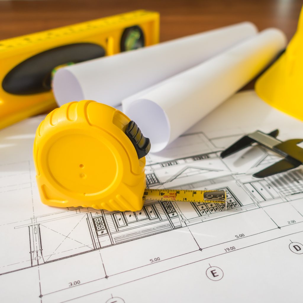 Architectural plans with measuring tape and level — recruitment for construction and engineering professionals